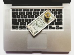 パソコンのキーボードに置かれた米国紙幣とコイン